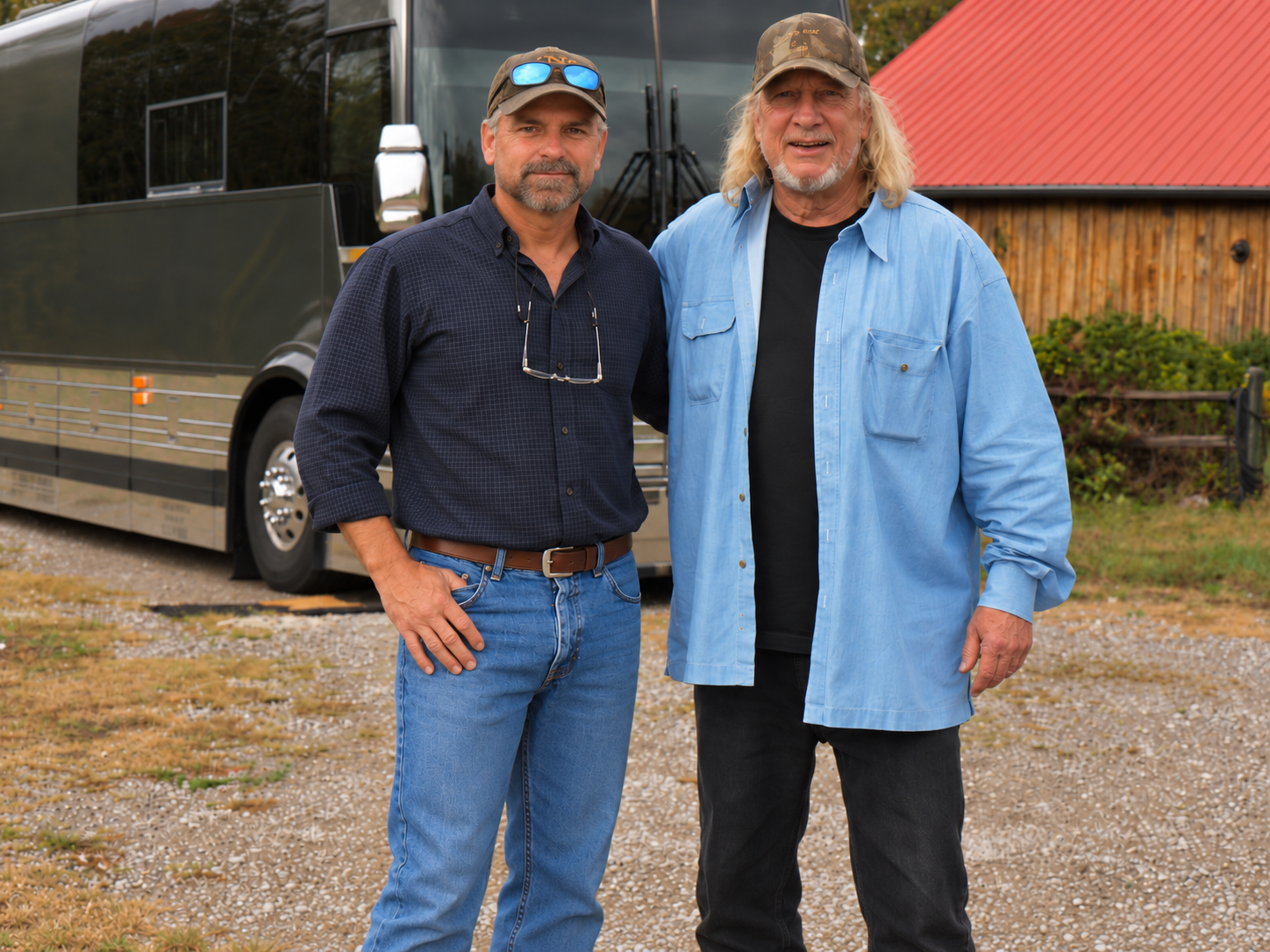 Two friends standing together beside a tour bus.